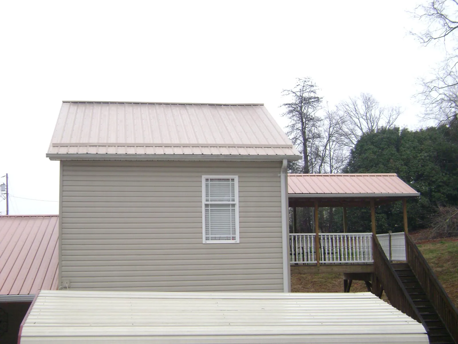 Tan metal roofs on a two story addition and attached porch, from a Roof Replacement job in New Lisbon