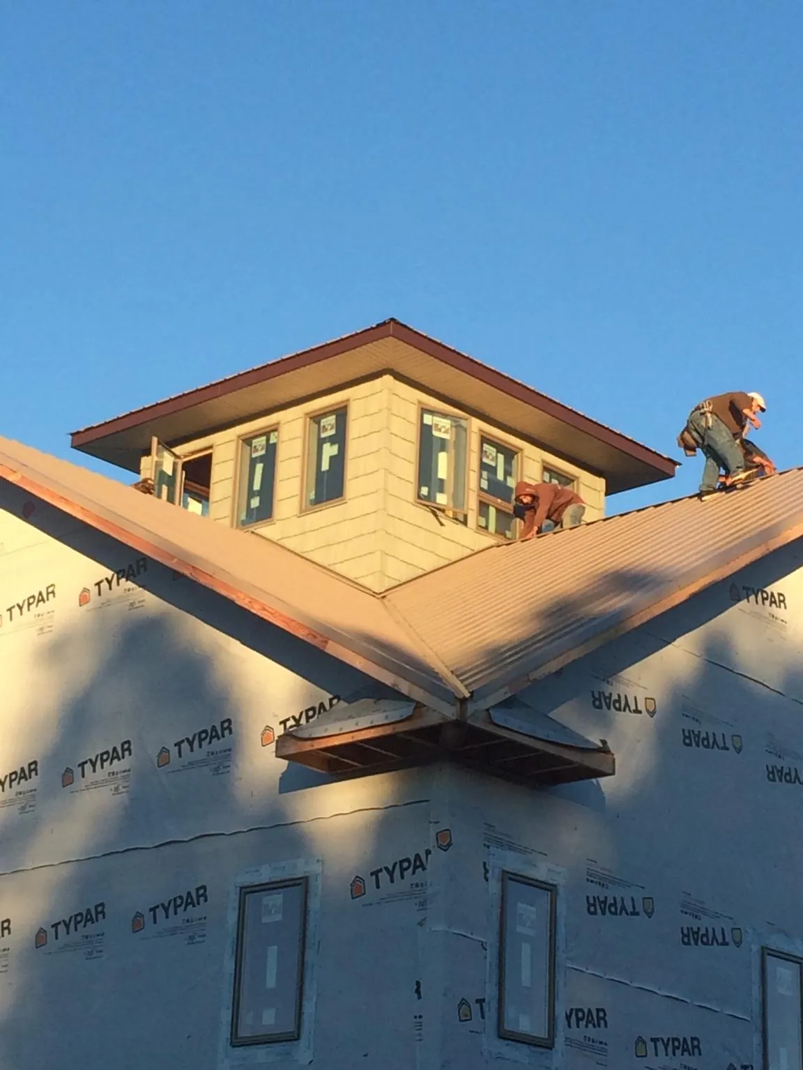 Roofers working around a rooftop cupola on a new metal roof at sunset — Roof Waterproofing in New Lisbon by Roofing Brothers